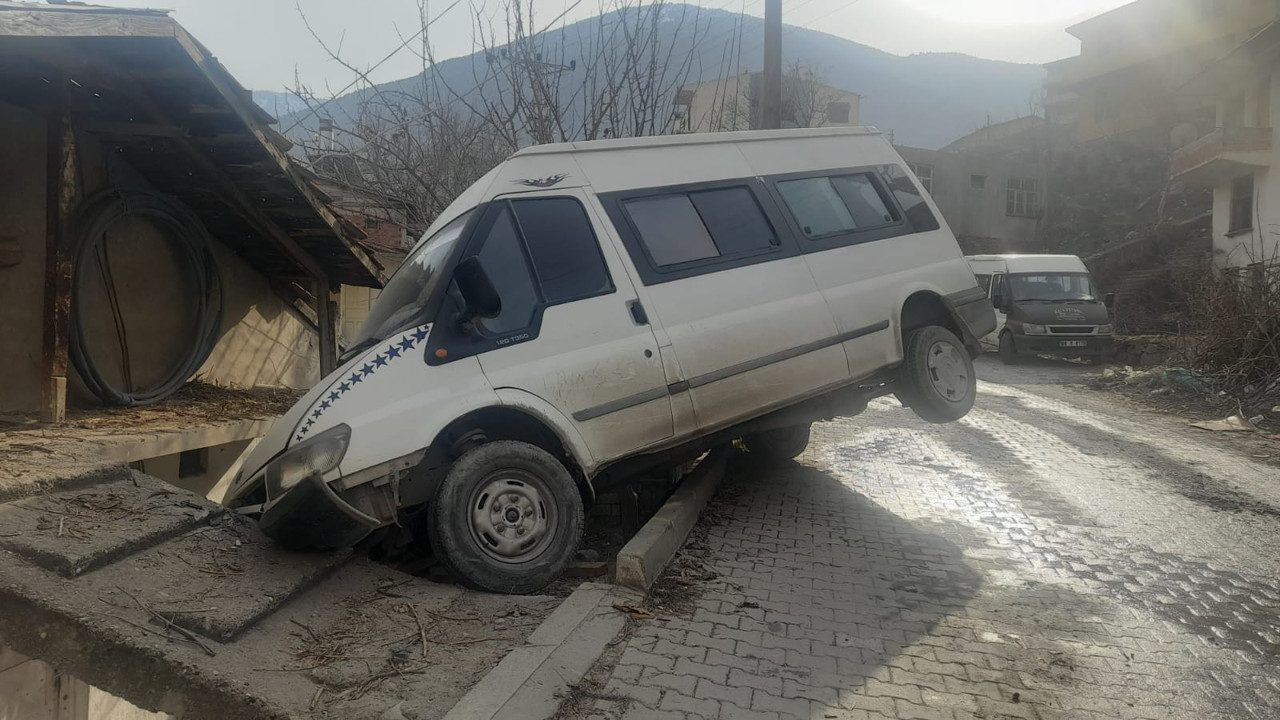 Buzlu yolda kayan minibüs askıda kaldı