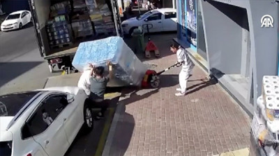 Devrilen yüzlerce kilo su yüklü paletin altında kaldılar. O anlar anbean kameraya yansıdı