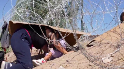 Genç bir kadının küçük çocuğuyla ABD’ye girmek için dikenli tellerle verdiği mücadelenin görüntüleri gündem oldu