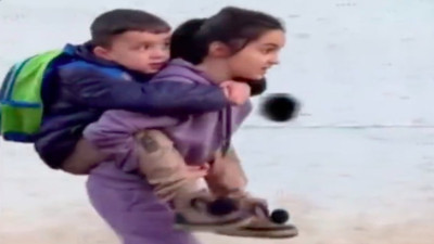 Küçük kardeşinin ayakları çamur olmasın diye sırtında taşıdı