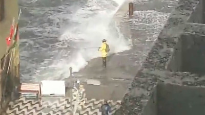 Dalgaların şiddetine aldırmadan balık tutmaya çalıştı