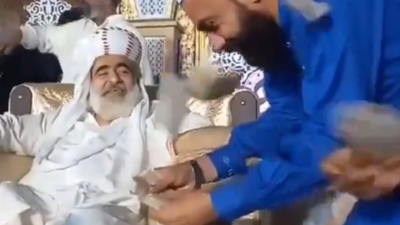 Tarikat lideri ayaklarını müritlere öptürüp para saçtı