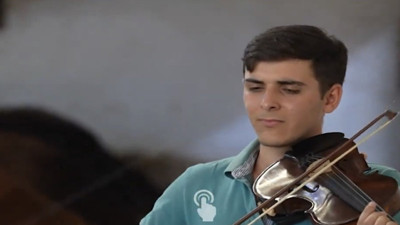 Genç besici kurbanlıklara keman çalarak bakıyor