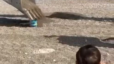 Sahilde oynayan çocuğun kum kovasını iş makinesi doldurdu
