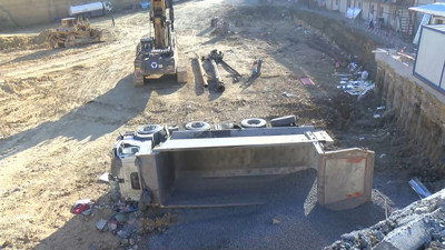 Hafriyat kamyonu geri geri gitti! Duvarı aşıp şantiye alanına devrildi