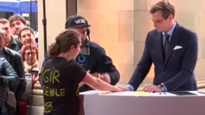 İklim aktivisti, canlı yayında elini sunucunun bulunduğu kürsüye yapıştırdı