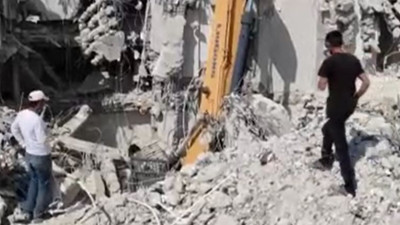 Ağır hasarlı binayı yıkan kepçe operatörü enkaz altında kaldı