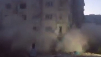 Depremlerde ağır hasar gören binayı taş atarak yıktı