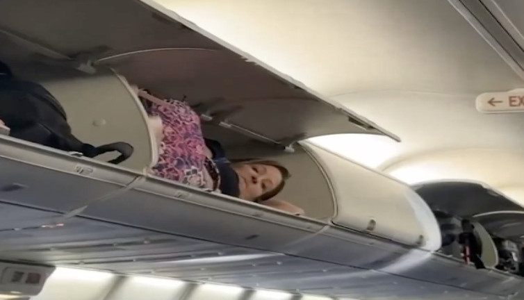 Uçakta ilginç görüntü: Bir yolcu valiz dolaplarına çıkarak uyumaya çalıştı
