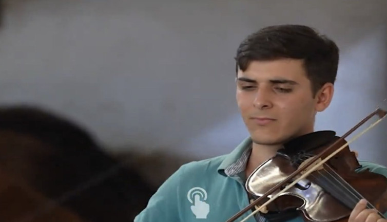 Genç besici kurbanlıklara keman çalarak bakıyor